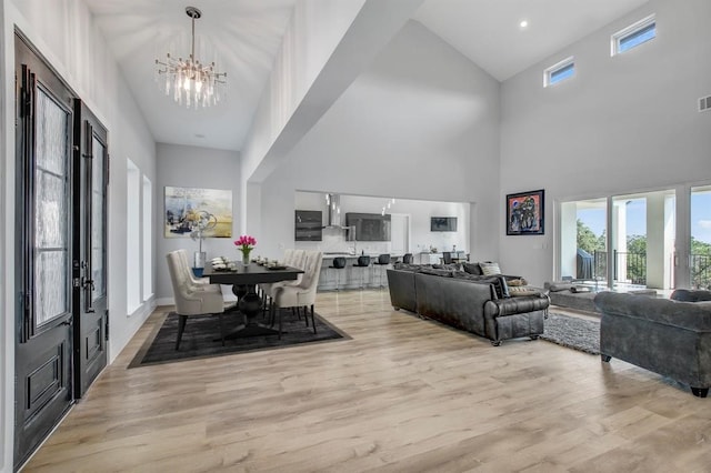 living room with high vaulted ceiling, light hardwood / wood-style floors, and an inviting chandelier