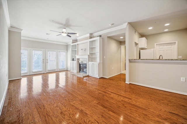 unfurnished living room with crown molding, ceiling fan, and light hardwood / wood-style floors