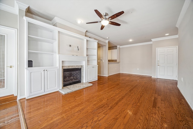 unfurnished living room featuring a high end fireplace, hardwood / wood-style flooring, ceiling fan, and crown molding