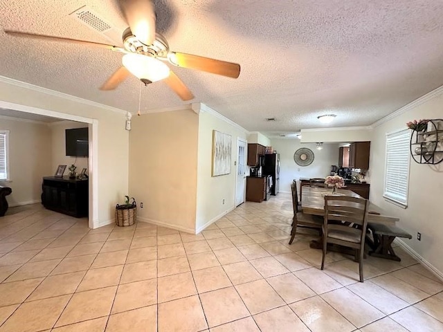 tiled dining space with ceiling fan, a textured ceiling, and ornamental molding