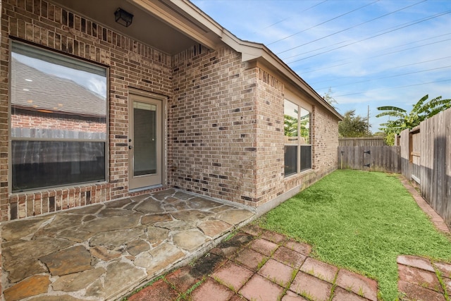 entrance to property featuring a lawn and a patio area