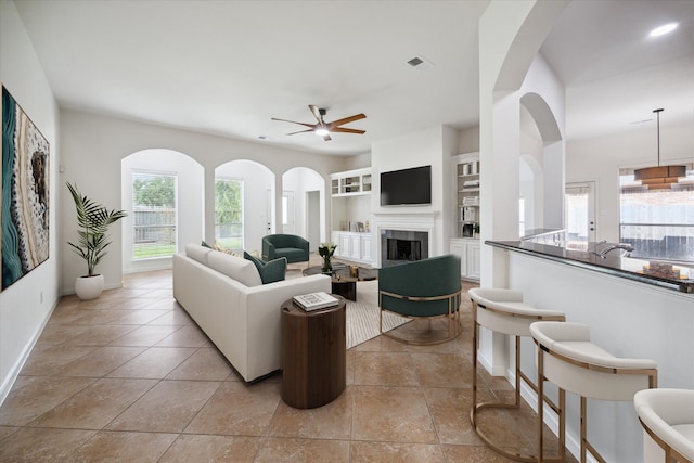 tiled living room with built in features and ceiling fan