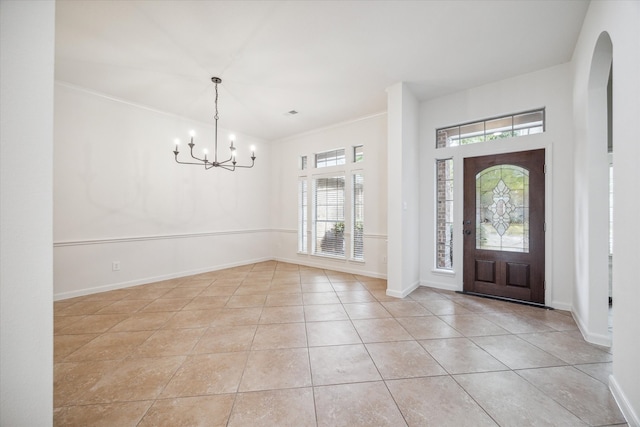 tiled foyer entrance with crown molding and a chandelier