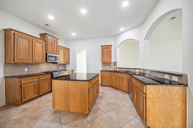 kitchen featuring kitchen peninsula, appliances with stainless steel finishes, tasteful backsplash, sink, and a kitchen island