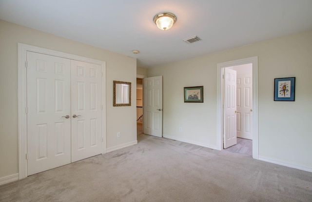 unfurnished bedroom with light colored carpet and a closet