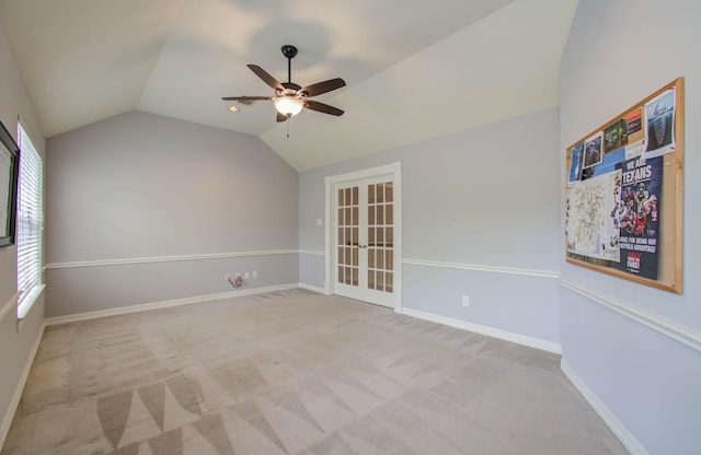 carpeted empty room with ceiling fan, vaulted ceiling, and french doors