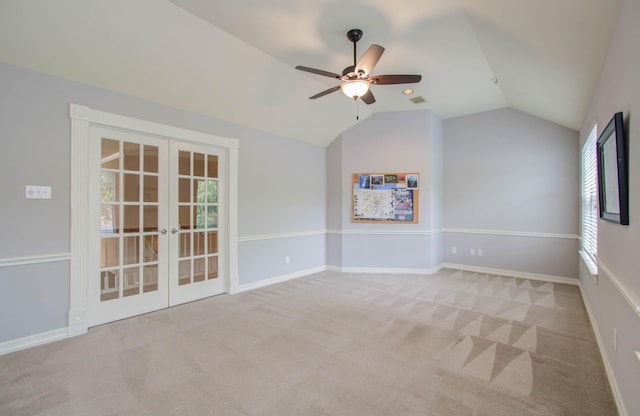 carpeted empty room with ceiling fan, french doors, and vaulted ceiling