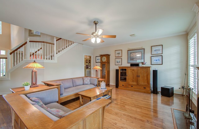 living room with ceiling fan, crown molding, and light hardwood / wood-style flooring