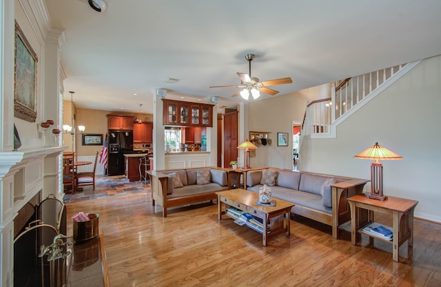 living room featuring ceiling fan with notable chandelier and light hardwood / wood-style flooring