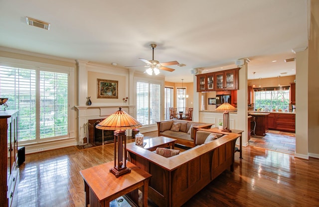 living room featuring ceiling fan, a high end fireplace, a healthy amount of sunlight, and dark hardwood / wood-style flooring