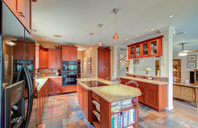 kitchen with ceiling fan, light stone countertops, a kitchen island, pendant lighting, and black appliances