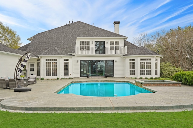 rear view of house featuring outdoor lounge area, a pool with hot tub, a patio area, and a balcony