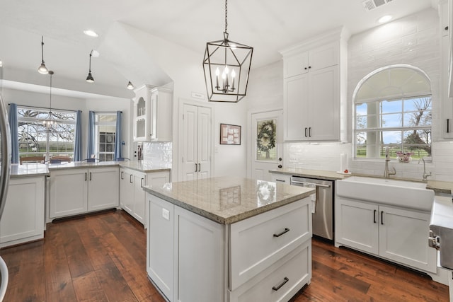 kitchen featuring decorative backsplash, white cabinets, stainless steel dishwasher, and dark hardwood / wood-style floors