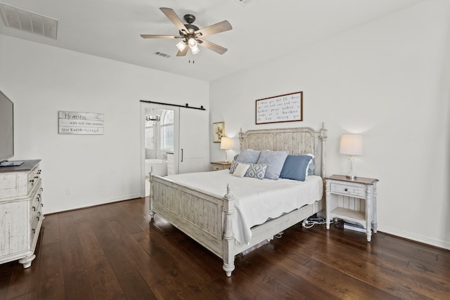 bedroom featuring a barn door, ensuite bathroom, ceiling fan, and dark wood-type flooring