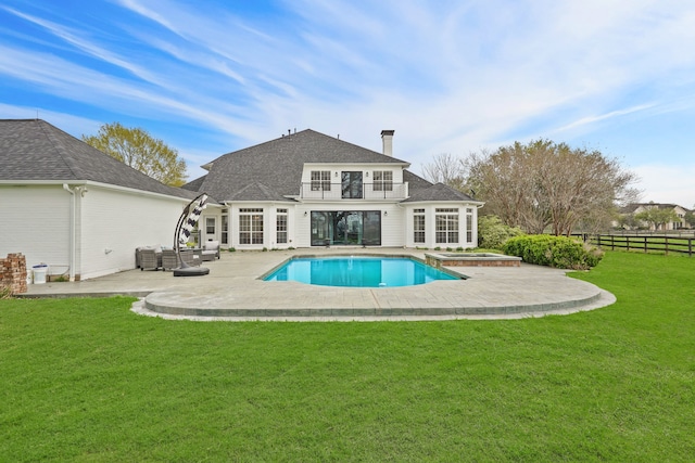 back of house featuring a pool with hot tub, a lawn, a patio, and a balcony