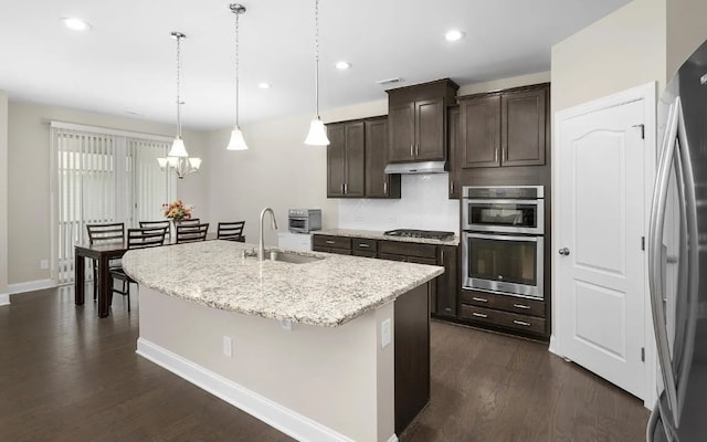 kitchen featuring appliances with stainless steel finishes, sink, a center island with sink, dark hardwood / wood-style floors, and hanging light fixtures