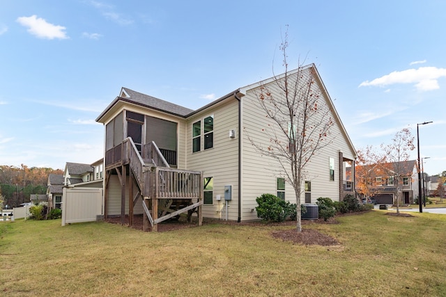 back of house featuring a sunroom, central AC, and a lawn