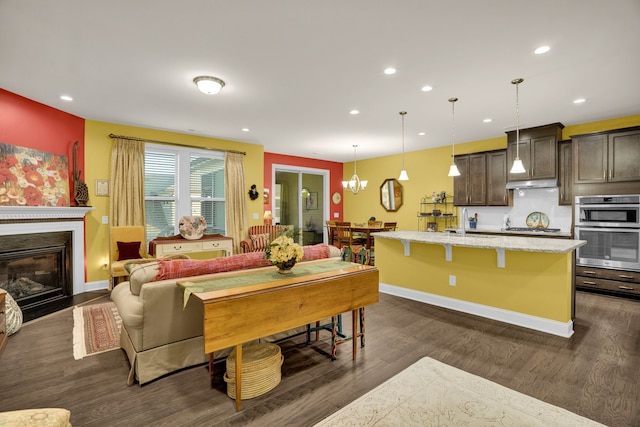 interior space featuring dark brown cabinetry, hanging light fixtures, a kitchen breakfast bar, dark hardwood / wood-style flooring, and a center island with sink