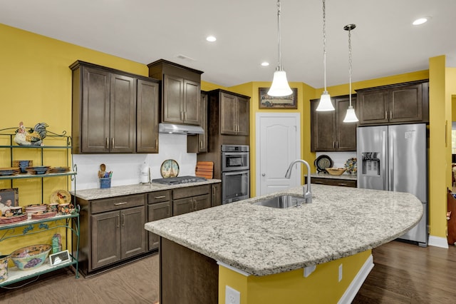 kitchen with dark hardwood / wood-style flooring, stainless steel appliances, a kitchen island with sink, sink, and hanging light fixtures