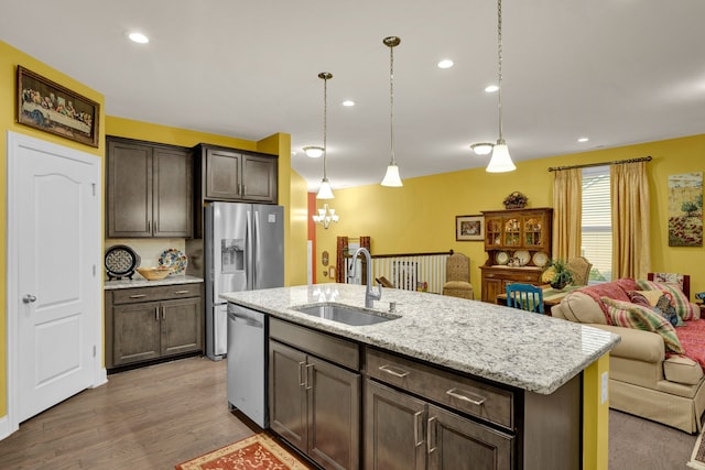 kitchen featuring dishwasher, sink, hanging light fixtures, hardwood / wood-style floors, and an island with sink