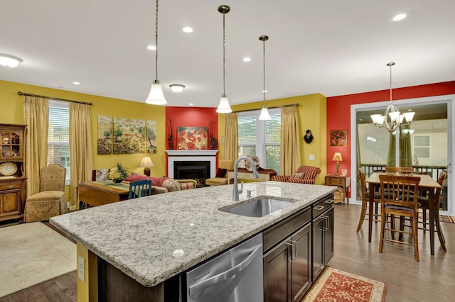 kitchen featuring dishwasher, sink, light wood-type flooring, an island with sink, and a chandelier