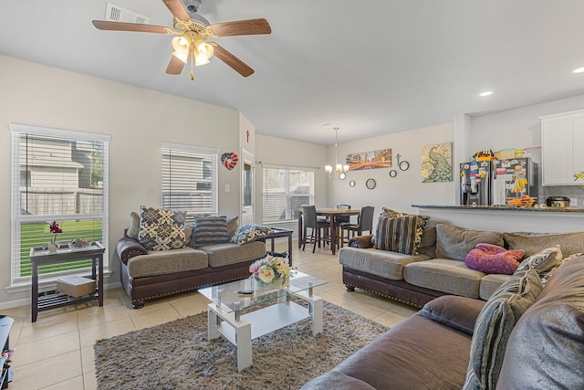 living room featuring light tile patterned flooring and ceiling fan with notable chandelier