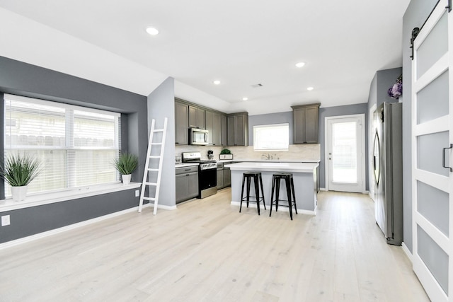 12810 Ilderton Dr, Humble, TX 77346 - kitchen with stainless steel appliances, a kitchen bar, a kitchen island, light countertops, and light wood-style floors