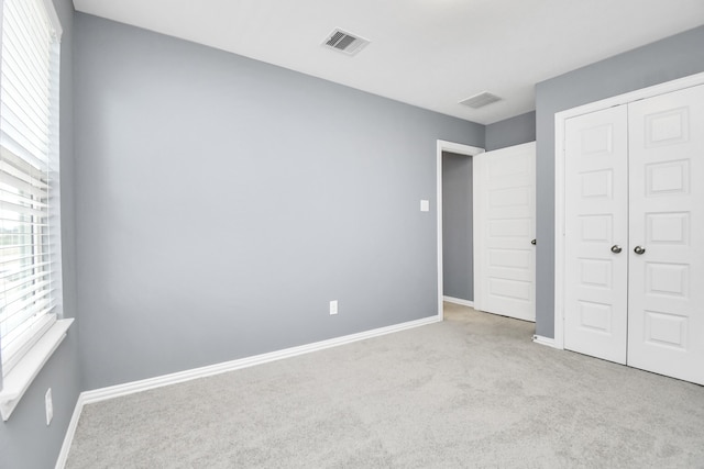 unfurnished bedroom with a closet and light colored carpet