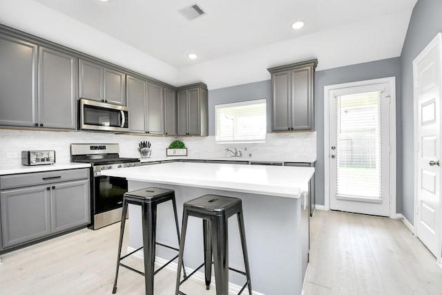 12810 Ilderton Dr, Humble, TX 77346 - kitchen with stainless steel appliances, a kitchen bar, gray cabinets, backsplash, and recessed lighting