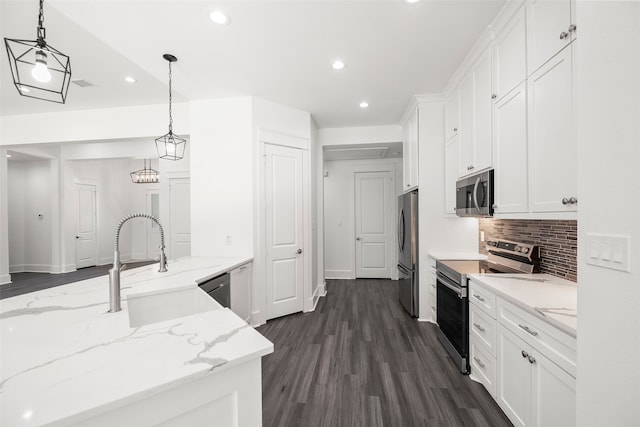 kitchen with light stone counters, stainless steel appliances, dark wood-type flooring, white cabinetry, and hanging light fixtures