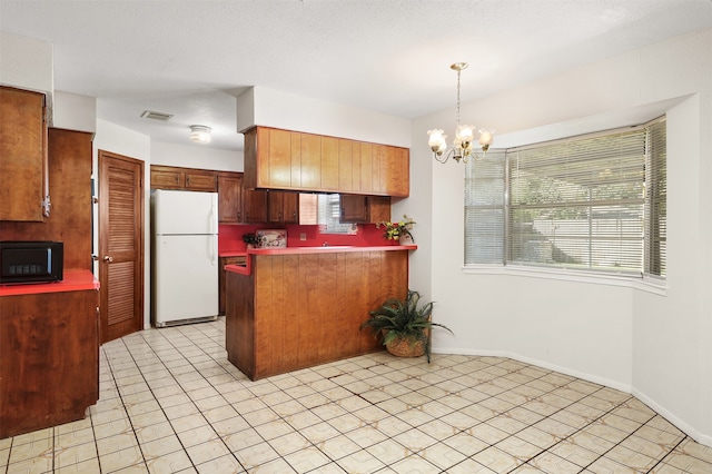 kitchen with light tile patterned flooring, white fridge, a notable chandelier, decorative light fixtures, and kitchen peninsula