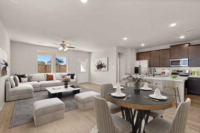 dining area featuring light hardwood / wood-style flooring, ceiling fan, and sink