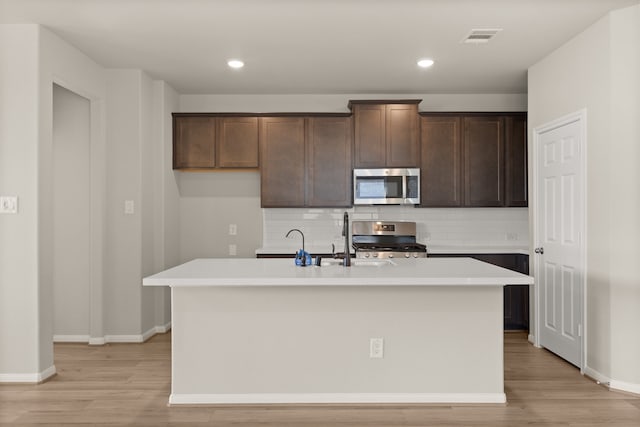 kitchen with an island with sink, stainless steel appliances, and light hardwood / wood-style floors