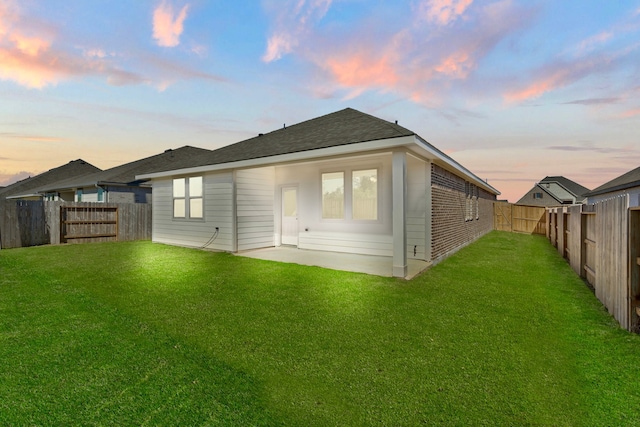 back house at dusk with a lawn