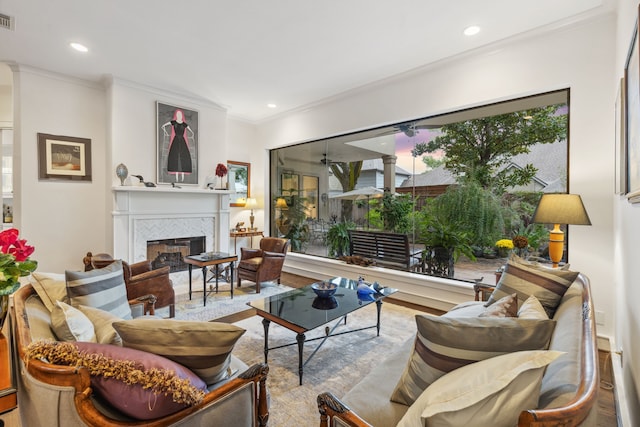 living room with a tile fireplace, light wood-type flooring, and ornamental molding