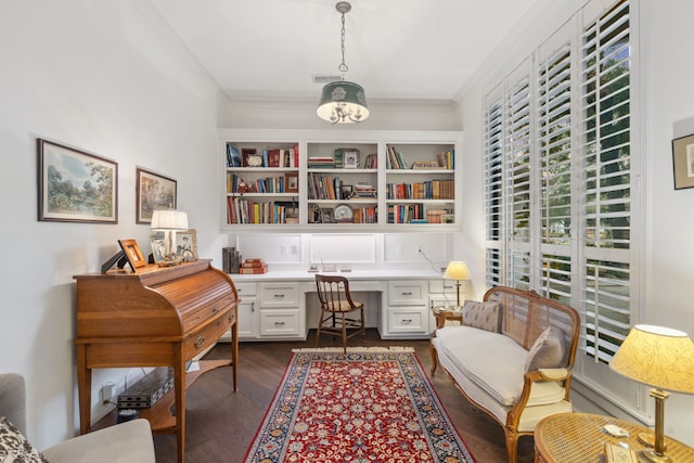 office space featuring built in desk, dark hardwood / wood-style floors, an inviting chandelier, and crown molding