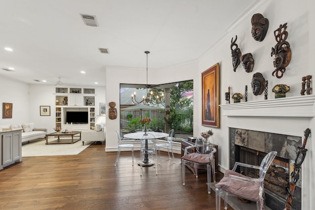 interior space with hardwood / wood-style floors, ceiling fan with notable chandelier, ornamental molding, and a tiled fireplace