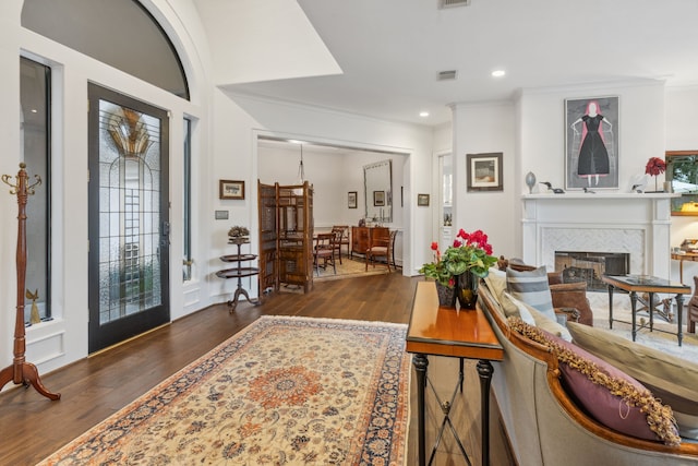 foyer entrance featuring crown molding, dark wood-type flooring, and a tiled fireplace