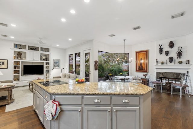 kitchen with a fireplace, a center island, hanging light fixtures, and ceiling fan with notable chandelier