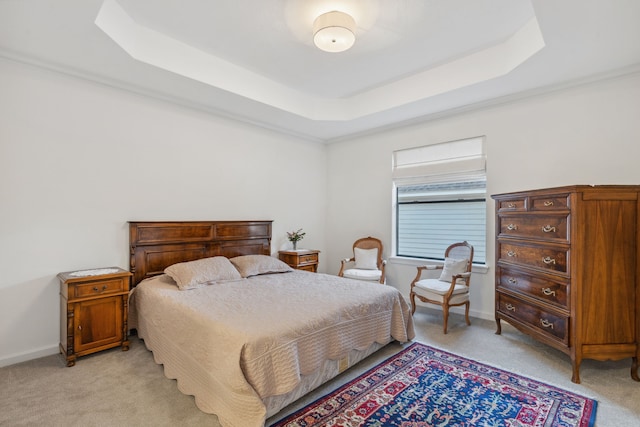 carpeted bedroom with a tray ceiling and ornamental molding