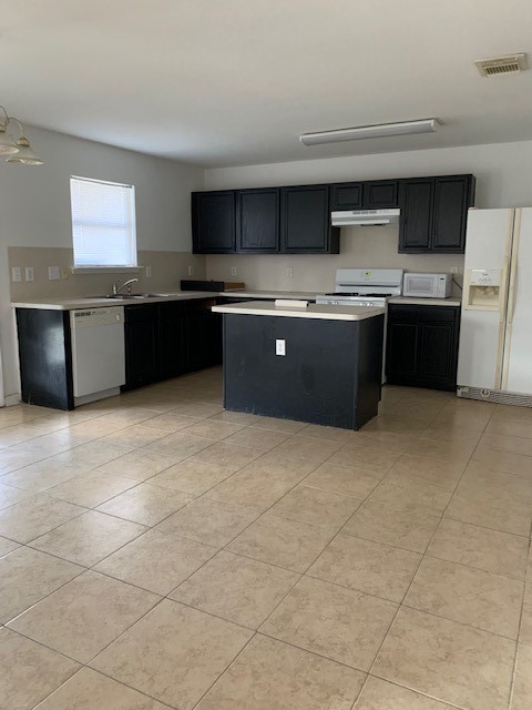 kitchen with white appliances, a center island, and sink