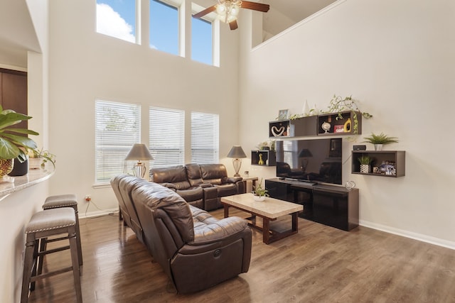 living room with ceiling fan, hardwood / wood-style floors, and a high ceiling