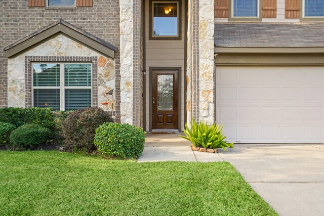 view of exterior entry with a garage and a lawn