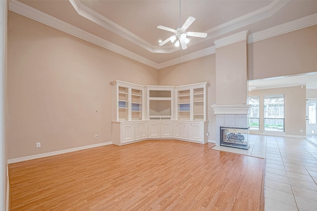 3110 Meadow Oak Dr, Houston, TX 77068 - unfurnished living room featuring a tray ceiling, a ceiling fan, a high ceiling, light wood-style flooring, and a tiled fireplace