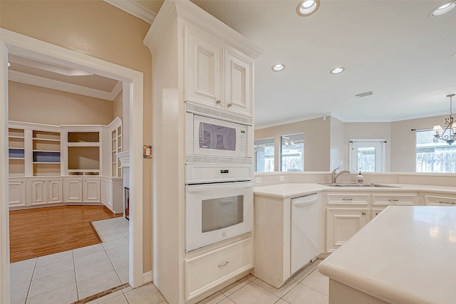 kitchen with sink, white appliances, crown molding, and light tile patterned flooring