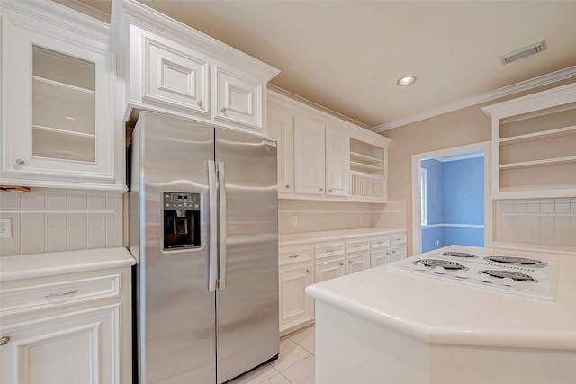 kitchen featuring white cabinets, white electric stovetop, decorative backsplash, stainless steel fridge, and light tile patterned floors