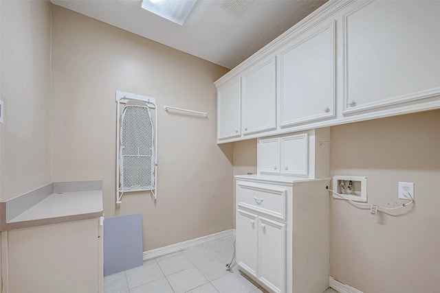 clothes washing area with cabinets, light tile patterned floors, and washer hookup