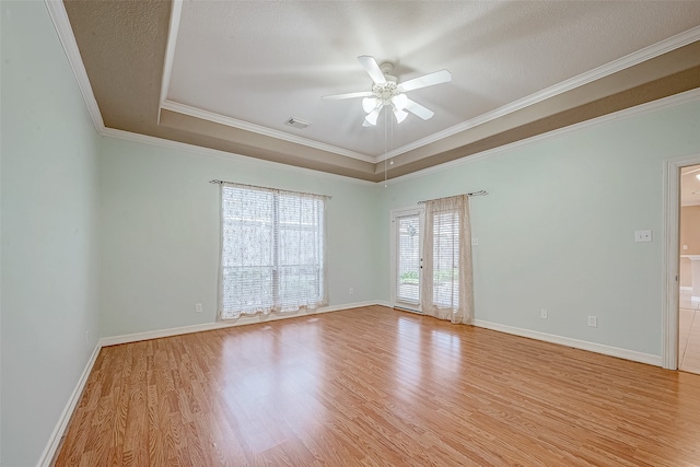 spare room featuring a textured ceiling, a raised ceiling, ceiling fan, crown molding, and light hardwood / wood-style floors