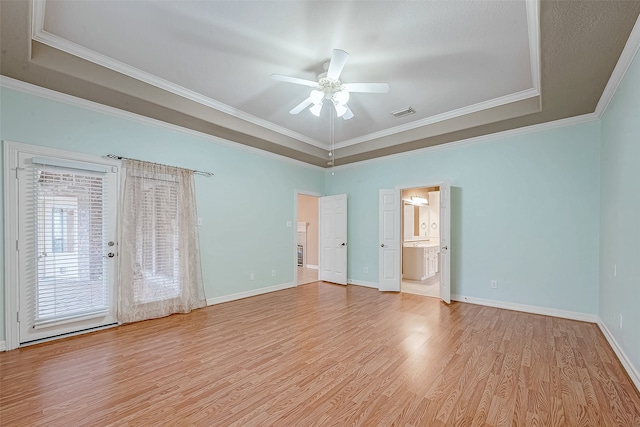 interior space with ensuite bath, a tray ceiling, ceiling fan, crown molding, and light hardwood / wood-style flooring