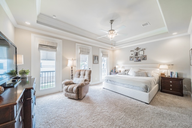 carpeted bedroom with a tray ceiling, ceiling fan, and crown molding